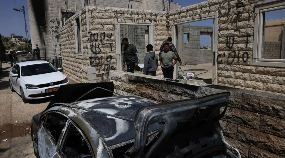 فلسطينيون يتفقدون مركبات مدمرة أمام منازلهم بعد هجوم لمستوطنين قرب مدينة الخليل بالضفة الغربية المحتلة (أ.ف.ب)
