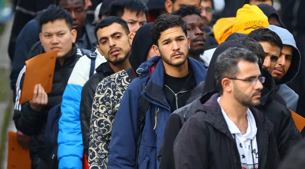 مهاجرون يصطفون أمام مركز استقبال طالبي لجوء في العاصمة الألمانية برلين (أرشيفية - رويترز)