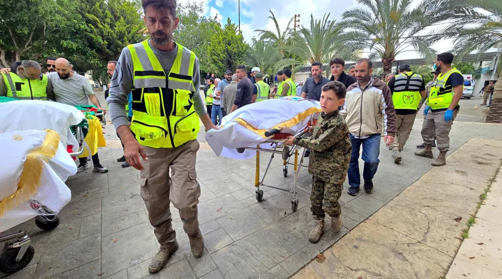 أشخاص يصلون برفقة جثامين ضحايا الغارة الإسرائيلية على قرية دير قانون النهر الجنوبية لبدء مراسم الدفن في منطقة صور بجنوب لبنان (أ.ف.ب)