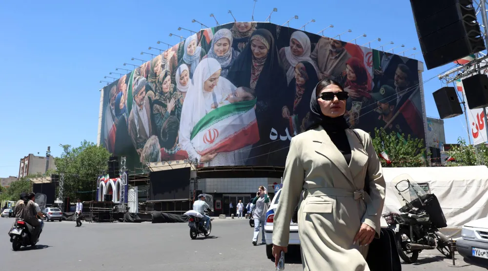 A woman walks next to a huge billboard in a street in Tehran, Iran, 25 May 2026. EPA/ABEDIN TAHERKENAREH
