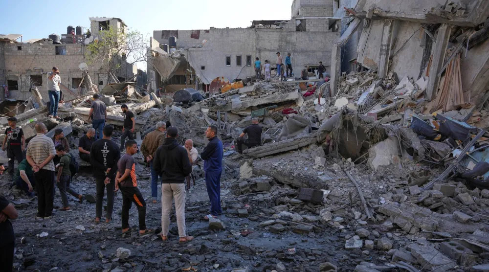 فلسطينيون يتفقدون أنقاض مبنى دمرته غارة جوية إسرائيلية في النصيرات - وسط قطاع غزة (أ.ب)