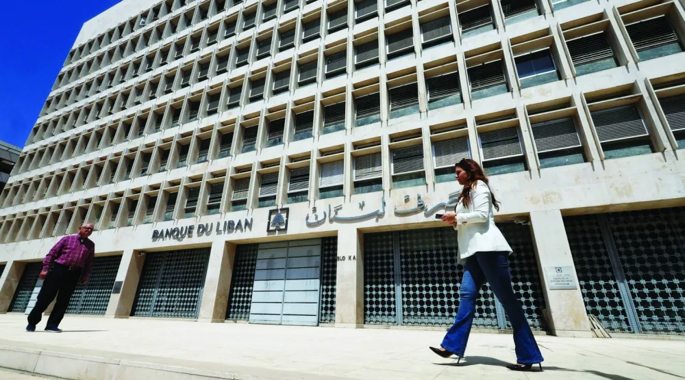 أشخاص يسيرون أمام مقر مصرف لبنان المركزي في منطقة الحمراء ببيروت (رويترز)
