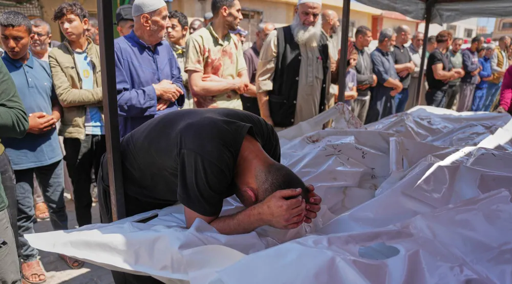 رجل ينحني فوق جثث فلسطينيين قتلوا في غارة إسرائيلية على مخيم المغازي للاجئين وسط غزة الثلاثاء (أ.ب)