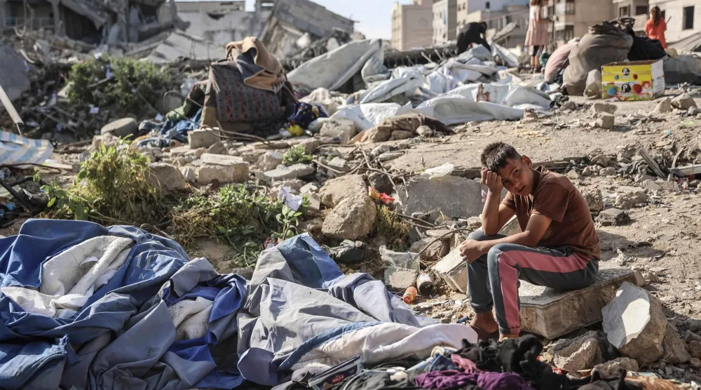 فتى فلسطيني يجلس في المكان الذي استهدف بغارة إسرائيلية أودت ليل أمس بحياة 10 أشخاص في مدينة غزة (أ.ف.ب)