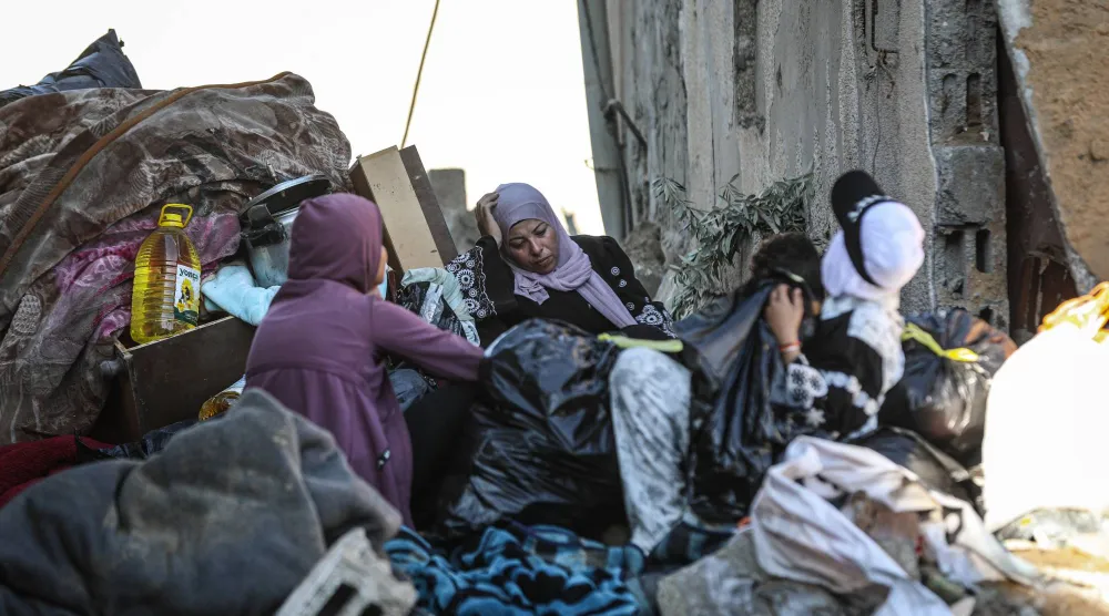فلسطينيات وسط دمار مبنى استهدفته غارة جوية إسرائيلية في دير البلح وسط قطاع غزة الجمعة (د.ب.أ)