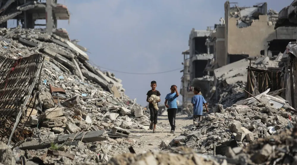 أطفال فلسطينيون يشقون طريقهم بين أنقاض المباني في مخيم الشاطئ للاجئين (أ.ف.ب)