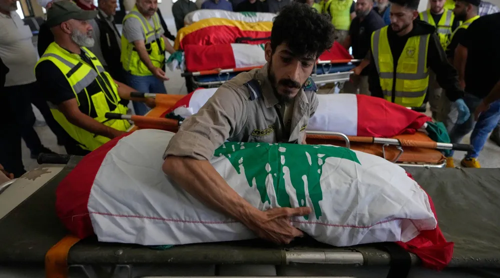 متطوعون في الدفاع المدني ينقلون نعوش 6 مدنيين قتلوا بغارة إسرائيلية أثناء إخلاء بلدتهم في جنوب لبنان (أ.ب)