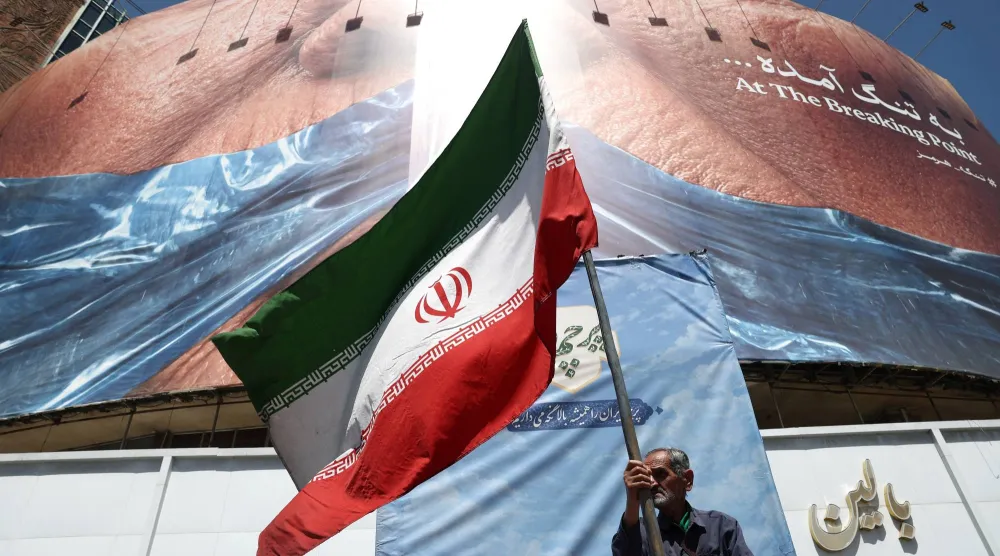 A man holds an Iranian flag near an anti-US billboard depicting US President Donald Trump and the Strait of Hormuz, in Tehran, Iran, May 30, 2026. Majid Asgaripour/WANA (West Asia News Agency) via REUTERS
