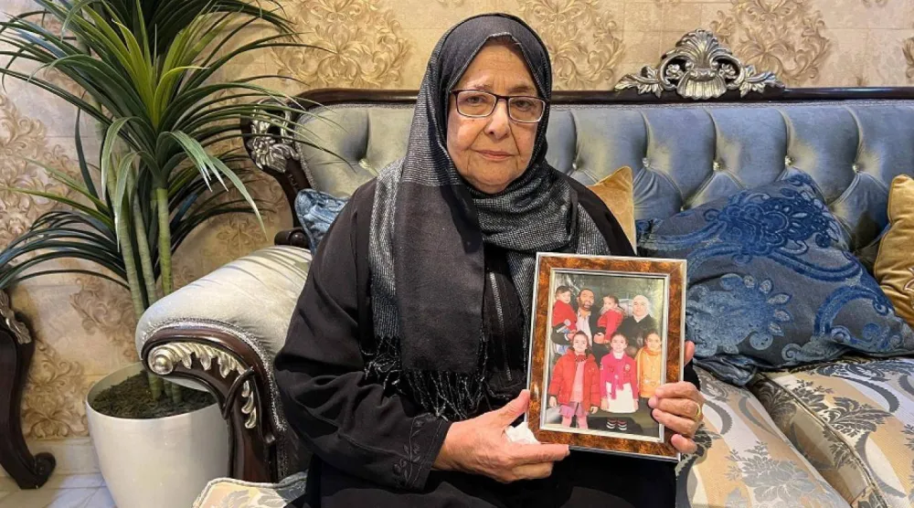 نجاح والدة رانيا العباسي تحمل صورة لابنتها وعائلتها (أ.ف.ب)