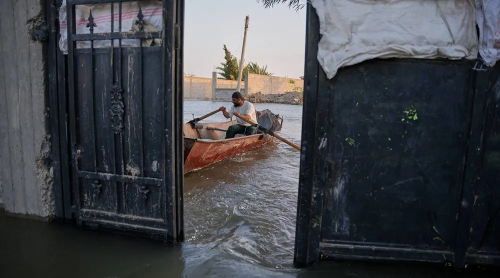 أحد السكان يجدّف بقارب صغير عبر مياه الفيضان خارج منزله الغارق على ضفاف نهر الفرات بالقرب من دير الزور الجمعة (أ.ب)
