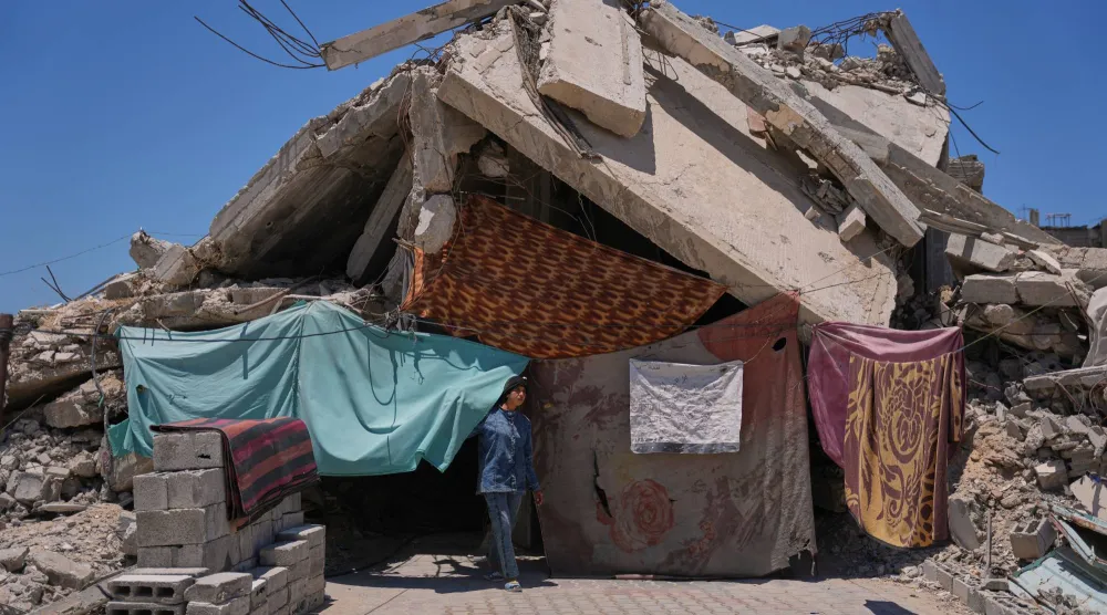 فلسطينية تقف يوم الجمعة الماضي أمام حطام منزل أسرتها الذي دمره الجيش الإسرائيلي في خان يونس جنوب غزة (أ.ب)