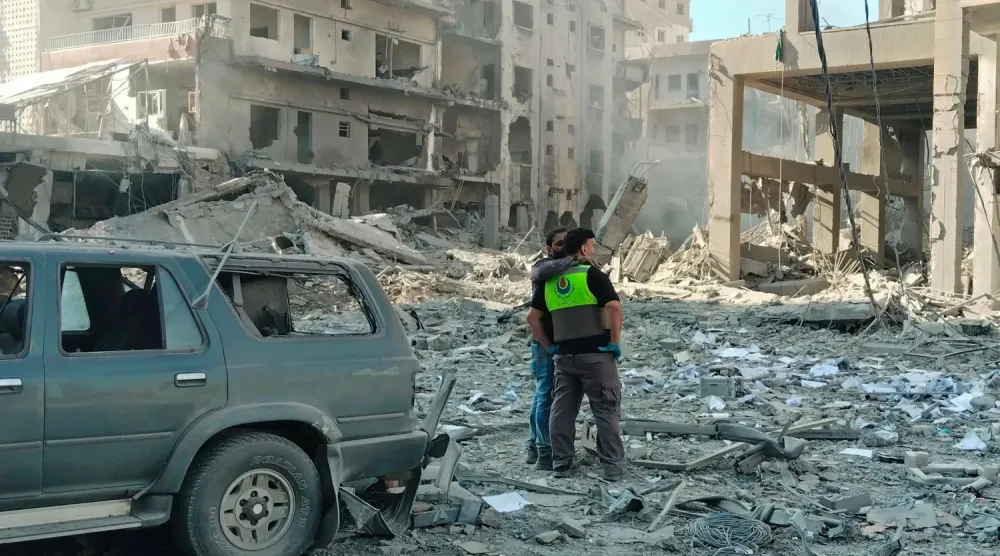 Lübnan Sivil Savunma güçleri, İsrail'in Sur şehrine düzenlediği hava saldırılarının yol açtığı hasarı inceliyor (AFP)