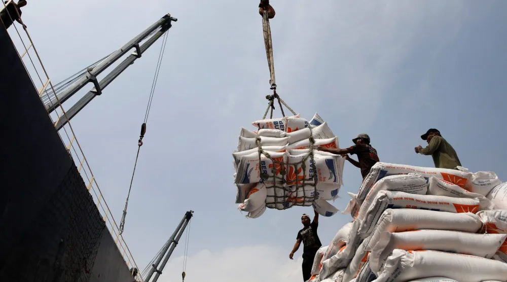 عُمال يفرغون أكياساً من الأرز من سفينة شحن إلى متن شاحنة في ميناء تانجونغ بريوك في جاكرتا (أرشيفية - رويترز)