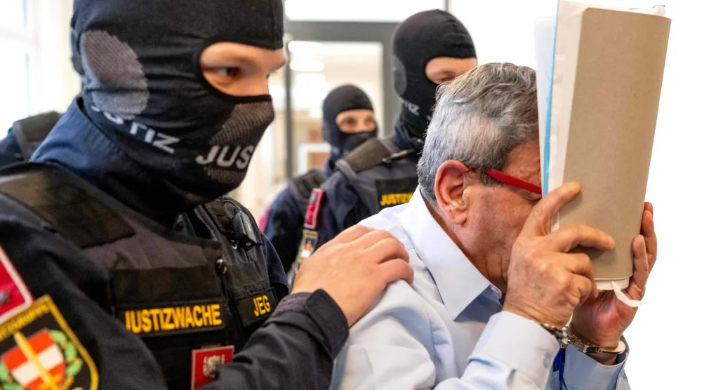 جنرال سوري سابق يدخل قاعة محكمة فيينا الإقليمية في النمسا الاثنين حيث يحاكَم وضابط شرطة سوري كبير بتهمة تعذيب معارضي نظام الأسد المخلوع (أ.ف.ب)
