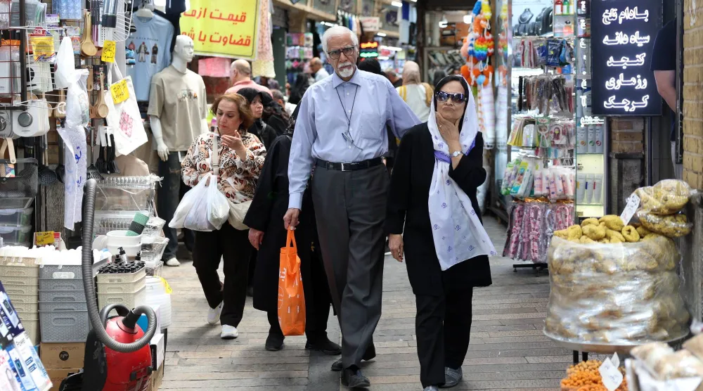 الناس يتسوقون في سوق بطهران (إ.ب.أ)