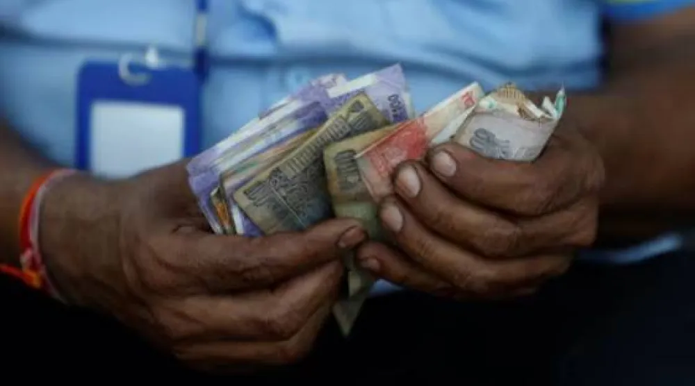 أمين صندوق يحمل أوراقاً نقدية هندية في محطة وقود بمدينة أحمد آباد في الهند (رويترز)