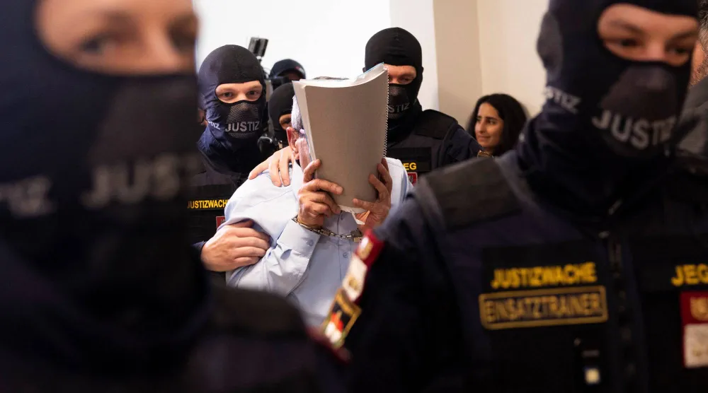 جنرال سوري سابق يدخل قاعة محكمة فيينا الإقليمية في النمسا الاثنين حيث يحاكَم وضابط شرطة سوري كبير بتهمة تعذيب معارضي نظام الأسد (أ.ف.ب)
