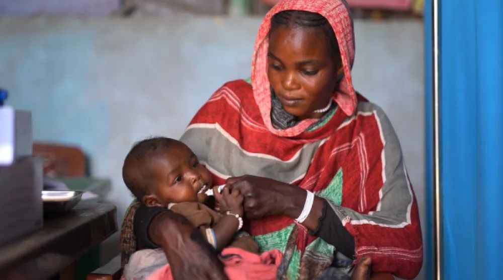 مواطنة سودانية تحاول إسكات جوع طفلها الرضيع (يونيسف)