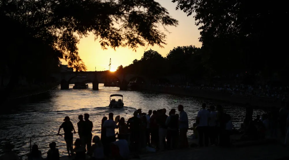 People gather on the banks of the Seine River as the sun sets amid a severe heat wave in Paris, France, May 26, 2026. (Reuters) 