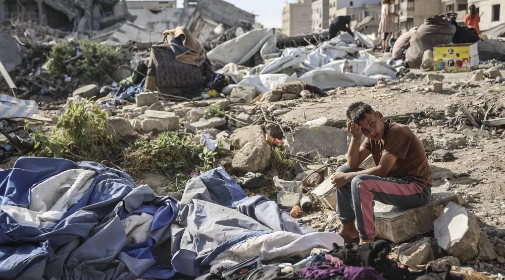  صبي فلسطيني يجلس في موقع غارة عسكرية إسرائيلية استهدفت مباني وخياماً تؤوي عائلات نازحة في غزة (أ.ف.ب)