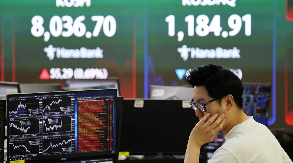 يعمل متداول فيما تعرض لوحة إلكترونية مؤشر«كوسبي» ومؤشر أسعار الأوراق المالية الكوري الآلي (كوسداك)، في غرفة تداول أحد البنوك في سيول (رويترز)