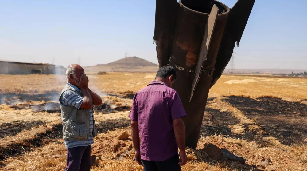 مزارعان سوريان بجانب صاروخ إيراني سقط بأرض زراعية في نجها بريف دمشق بعد أن اعترضته أنظمة الدفاع الجوي الإسرائيلية يوم 8 يونيو 2026 (أ.ف.ب)