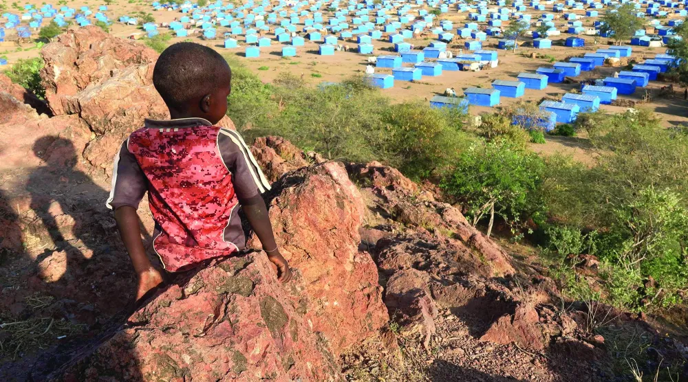 طفل يجلس على قمة تل مطل على مخيم للاجئين قرب الحدود السودانية مع تشاد في نوفمبر 2023 (رويترز)
