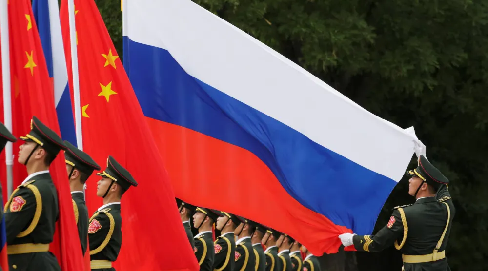 ضابط يمسك بالعلم الروسي قبل حفل ترحيب يقيمه الرئيس الصيني شي جينبينغ للرئيس الروسي فلاديمير بوتين... خارج «قاعة الشعب الكبرى» في بكين بالصين يوم 8 يونيو 2018 (رويترز)