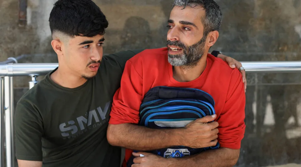 الفلسطيني يوسف سلمان يحمل الحقيبة المدرسية لابنه جاد (8 سنوات) بعد مقتله في غارة إسرائيلية على مخيم جباليا للاجئين بمدينة غزة الاثنين (رويترز)
