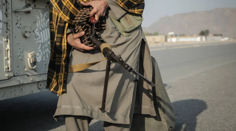 أحد مقاتلي «طالبان» يفحص سلاحه بجوار مركبة مدرعة عند نقطة تفتيش بالقرب من معبر حدودي بين باكستان وأفغانستان (د.ب.أ)