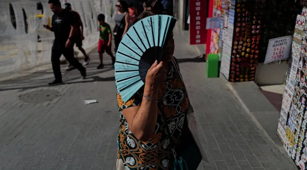 امرأة تحمل هواية يدوية في أثناء سيرها خلال موجة حر ربيعية في مدريد بإسبانيا خلال مايو 2026 (رويترز)
