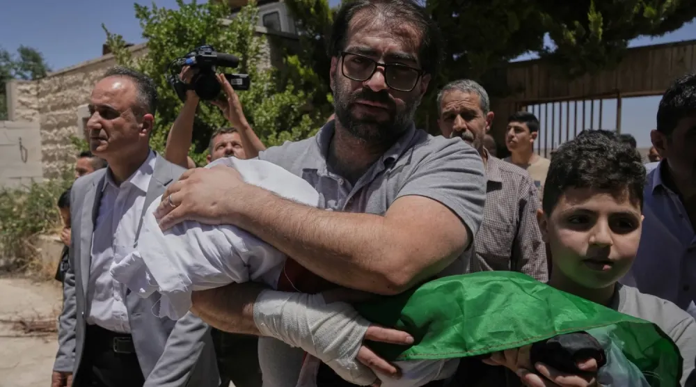 Fahd Ebu Heykel, geçen cuma günü İsrail askerleri tarafından öldürülen henüz bebek olan oğlu Sam'ın cesedini taşıyor (AP)