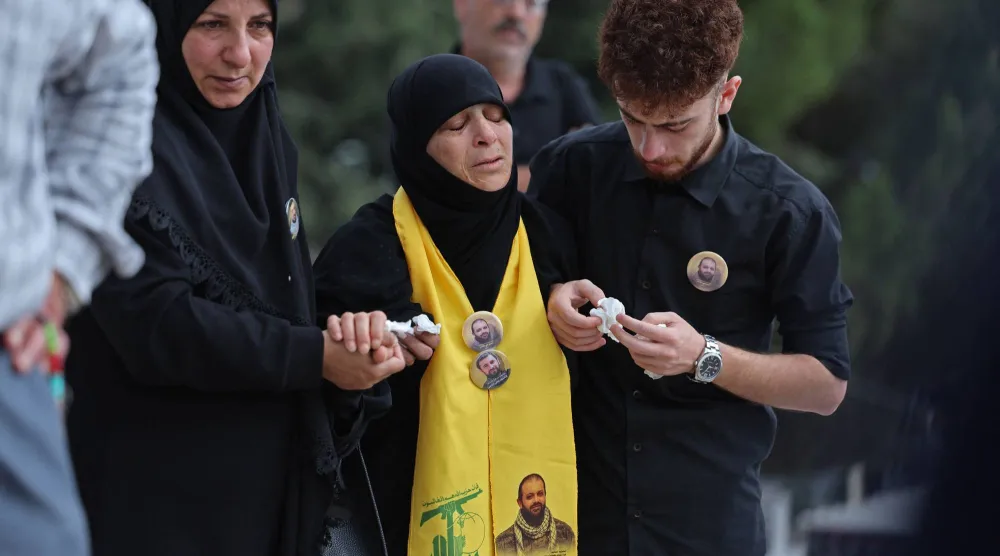 والدة مقاتل من «حزب الله» تبكيه خلال تشييعه بمقبرة مؤقتة في حارة صيدا جنوب لبنان (أ.ف.ب)