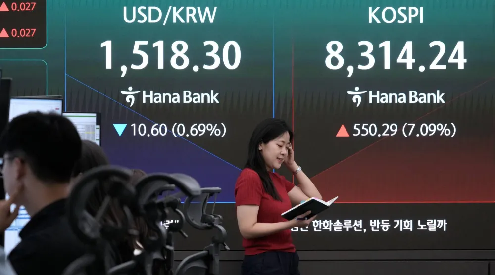 متداول عملات يتابع أداء مؤشر «كوسبي» وسعر صرف الدولار مقابل الوون في مقر بنك هانا بسيول (أ.ب)