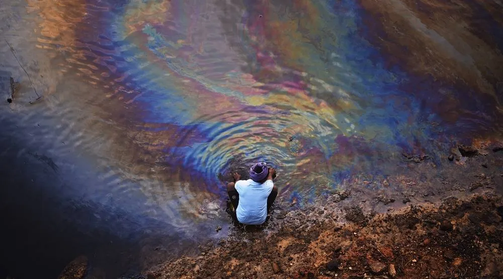 An Indian fisherman washes his hands in the waters of Ennore Creek covered with an oil spill after Cyclone Michaung, in Chennai, India, 11 December 2023. (EPA)