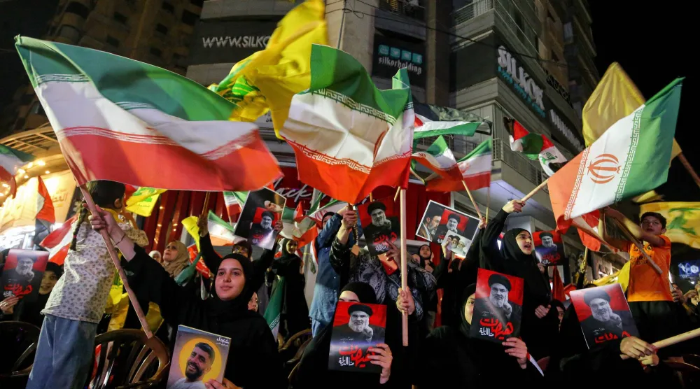 مناصرون لـ«حزب الله» يرفعون أعلامه وأعلام إيران خلال مسيرة داعمة لطهران في ضاحية بيروت الجنوبية (د.ب.أ)