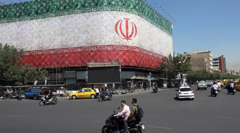 Iranians drive past a billboard featuring Iran's national flag at Enqelab Square in Tehran, Iran, 14 June 2026. EPA/ABEDIN TAHERKENAREH 
