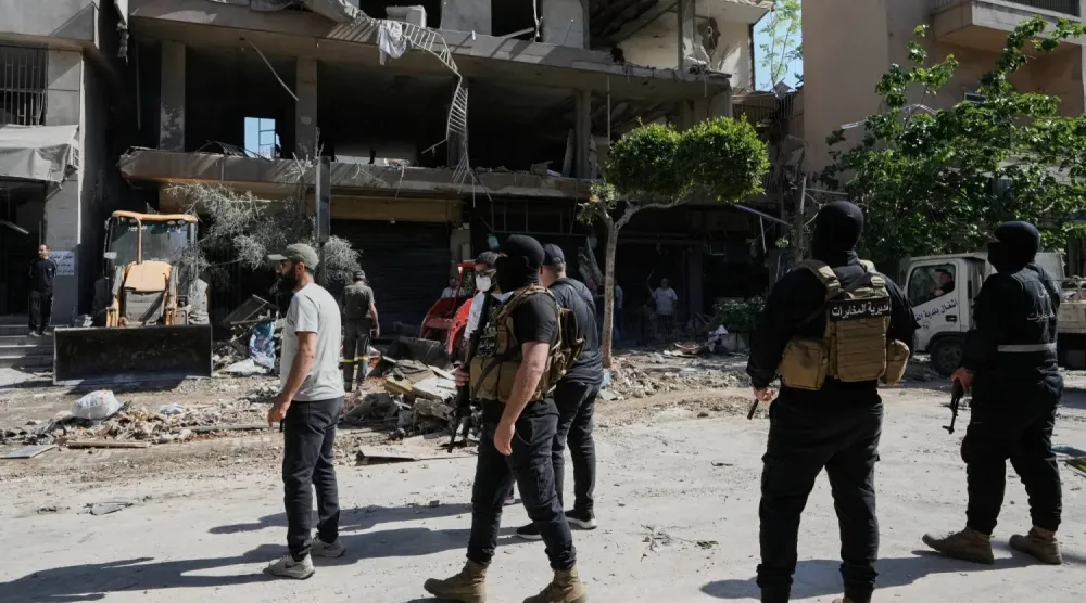 Dün Beyrut'un güney banliyösünde İsrail tarafından hedef alınan bir apartmanın önünde duran Lübnan Askeri İstihbarat üyeleri (AP)