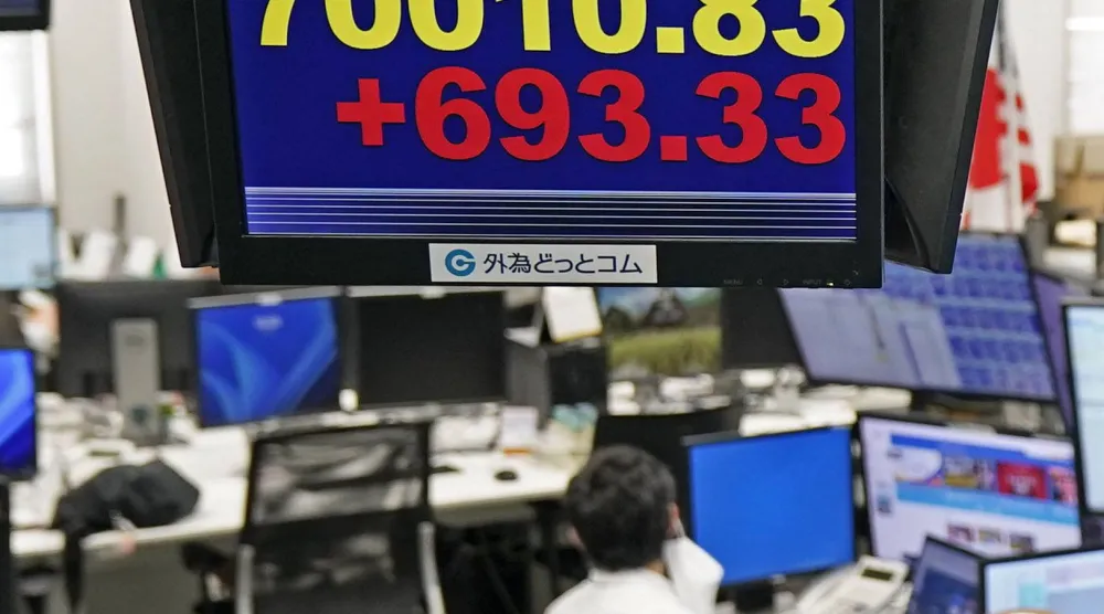 موظف في شركة تداول العملات الأجنبية يعمل تحت لوحة إلكترونية تعرض مؤشر«نيكي 225» الياباني، في طوكيو (أ.ب)