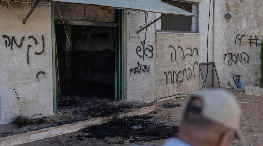 فلسطيني يمر بجانب مسجد متضرر بعدما أضرم مستوطنون إسرائيليون فيه النار في جلجليا بالضفة الغربية (أ.ف.ب)