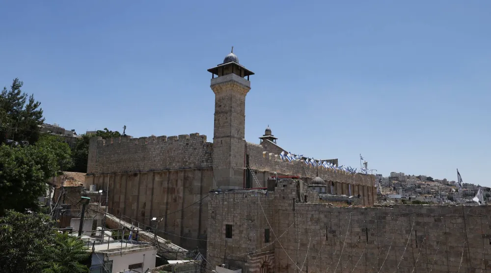 المسجد الإبراهيمي في البلدة القديمة بالخليل في الضفة الغربية المحتلة وعلى أحد جوانبه ترفع أعلام إسرائيلية يوم الأربعاء (رويترز)