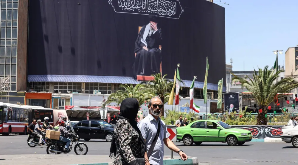 إيرانيون يمرّون أمام لوحة إعلانية تصوّر المرشد الإيراني الراحل علي خامنئي في ساحة في طهران يوم 15 يونيو 2026 (أ.ف.ب)
