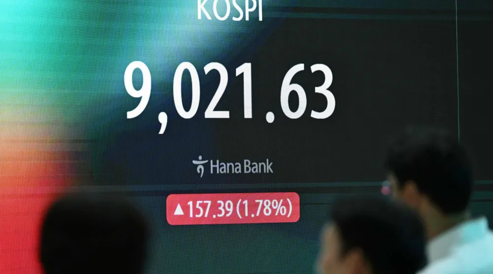 متداول عملات يقف أمام شاشة تظهر مؤشر الأسهم القياسي لكوريا الجنوبية الذي كسر 9000 نقطة في مقر بنك هانا في سيول (أ.ف.ب)
