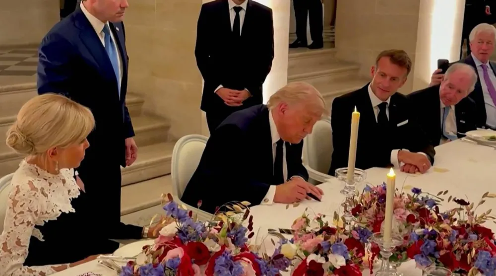 الرئيس الأميركي دونالد ترمب وهو يوقع على الاتفاق في فرنسا (أ.ف.ب)