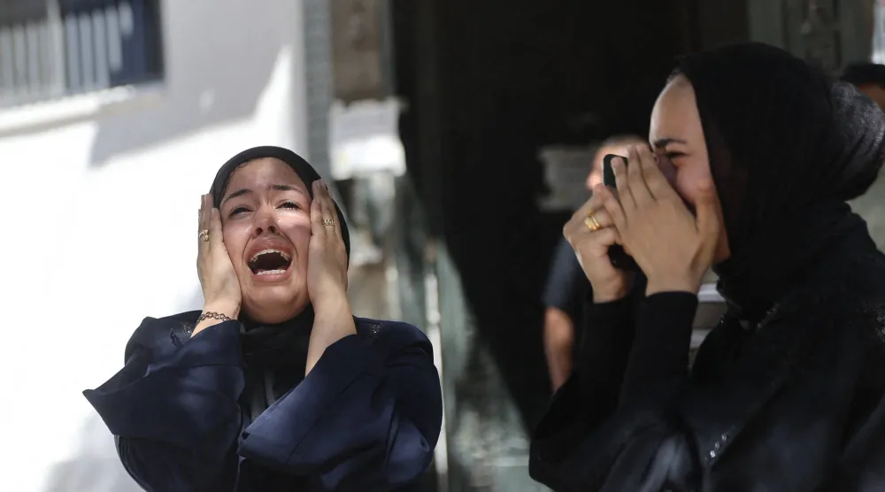 فلسطينيتان تصرخان خلال تشييع جنازة رجل قُتل في غارة إسرائيلية بمدينة غزة الخميس (أ.ف.ب)
