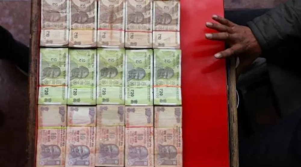 بائع يعرض أوراقاً نقدية هندية متنوعة في كشك لصرف العملات في دلهي القديمة (رويترز)