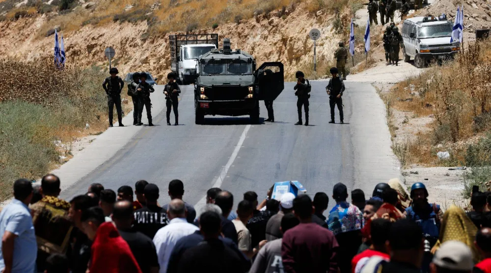 الجيش الإسرائيلي يغلق الطريق في حين يحتج فلسطينيون على الاستيطان قرب الخليل بالضفة الغربية المحتلة الجمعة (رويترز)