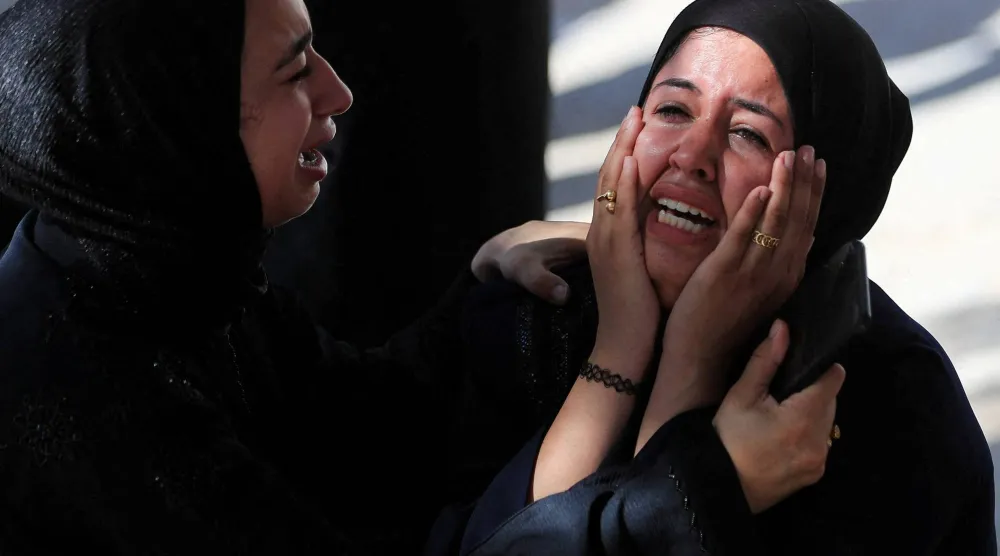 فلسطينيتان تبكيان أقارب لهما قتلوا بهجوم إسرائيلي خلال تشييعهم في مدينة غزة الخميس (رويترز)
