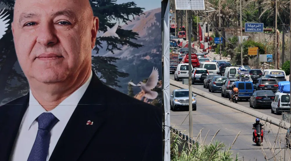 صورة عملاقة للرئيس اللبناني جوزيف عون مثبتة على المدخل الشمالي لمدينة صيدا وتظهر في الصورة سيارات النازحين من الجنوب باتجاه بيروت (إ.ب.أ)