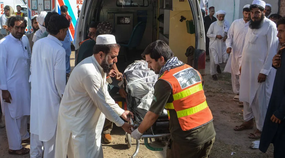 نقل متطوعون جثمان أحد ضحايا تفجيرين متزامنين على جانب الطريق إلى مستشفى في بانو (أ.ف.ب)